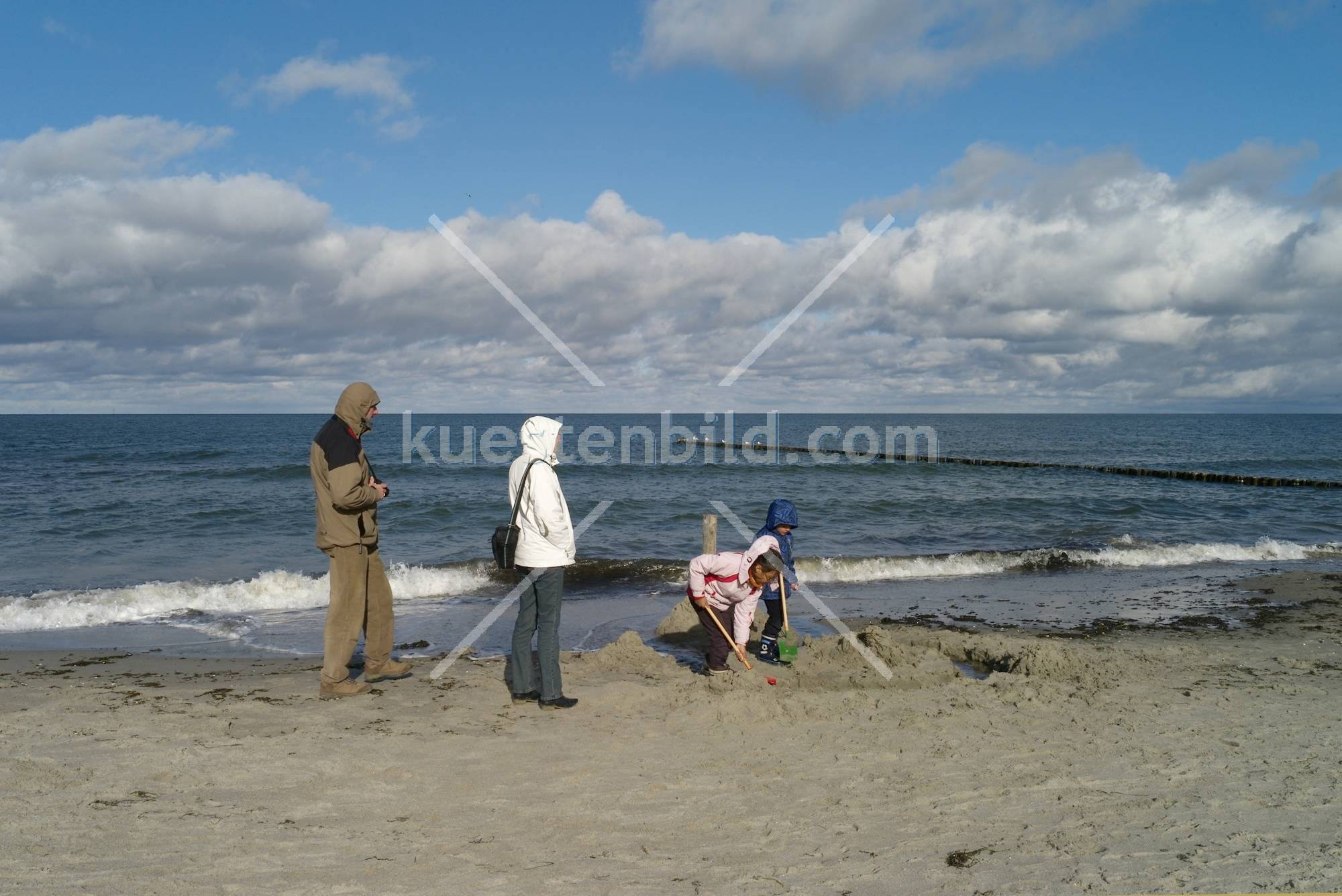 Familie mit Kindern beim Sandschaufeln